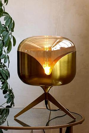 Lifestyle image of the Retro Golden Glass Tripod Table Lamp lit up
