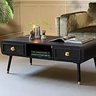 A black coffee table styled with a lit candle and various accessories.