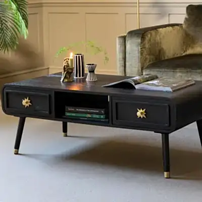 A black coffee table styled with a lit candle and various accessories.
