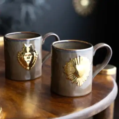 Two milagor heart mugs styled on a dark wooden surface.
