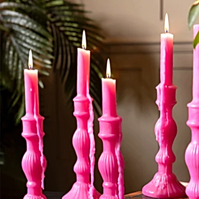 Several hot pink candles, lit with candle wax running down them.