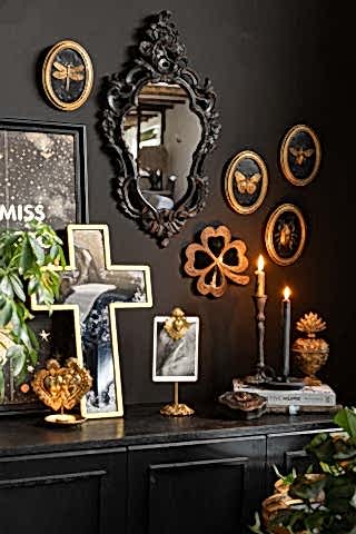 The Beautiful Ornate Black Wall Mirror shown in a gothic glam scene, with other black and gold vintage wall art shown on the walls above a sideboard. 