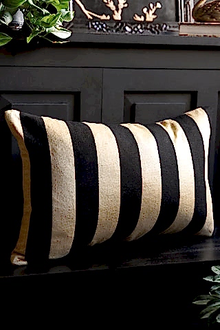 The Black & Gold Stripe Cushion Cover styled on a black bench.