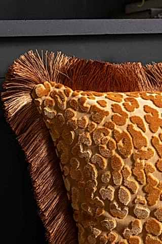 Close-up of the corner of the Ochre Leopard Velvet Cushion with Fringe Trim.