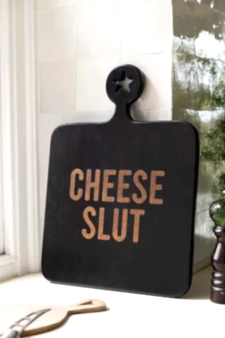 The Cheese Slut Square Wooden Serving Board shown in a kitchen against white zellige tiles. 