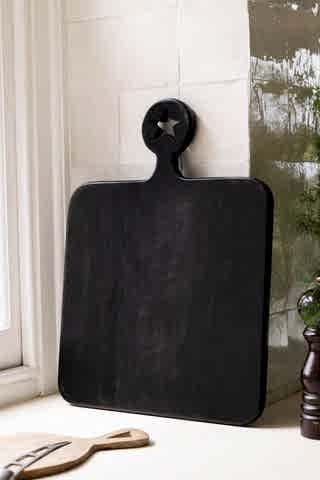 The back of the Cheese Slut Square Wooden Serving Board shown in a kitchen against white zellige tiles. 