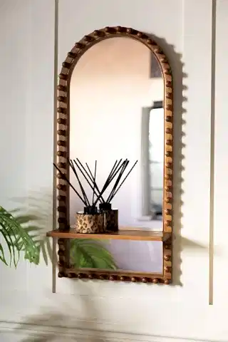 The Dark Wood Bobbin Mirror With Shelf shown on a panelled wall with a diffuser on the shelf.
