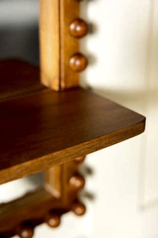 The corner of the shelf on the Dark Wood Bobbin Mirror With Shelf. 