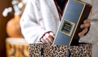 Someone placing a Rockett St George 'Thank Fuck For You' room diffuser into a leopard print gift bag.