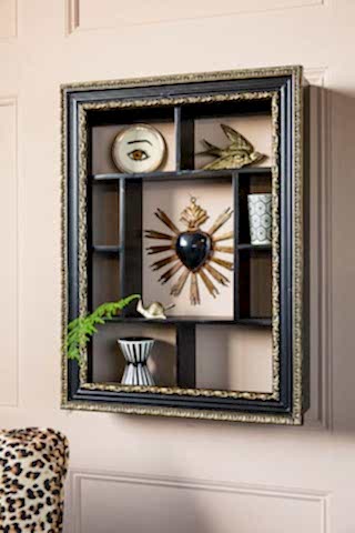 The Ornate Black & Gold Framed Wall Shelf styled with various accessories inside, styled on a wall.