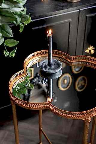 A closer detail of the Lucky Clover Mirrored Side Table, shown styled against a black cabinet with a grey candle on the top.