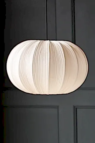 The Neutral Pleated Fabric Ceiling Light, hanging from a black cord, against a dark grey wall 