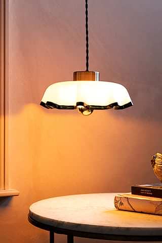 The Pink Pleated Glass Easyfit Ceiling Light Shade shown against plaster pink walls with the lights on. 