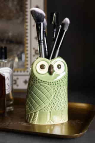 The Quirky Green Owl Bud Vase styled with makeup brushes inside, displayed on a trinket tray with some perfume.