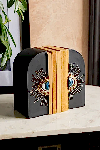 The Set of 2 Black Mystic Eye Bookends shown on a marble sideboard against plaster walls. 