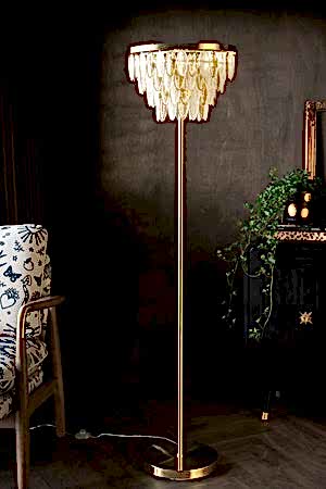 The Stunning Art Deco Glass Feather Floor Lamp styled next to a patterned amrchair and a sideboard with a plant and a gold frame on.