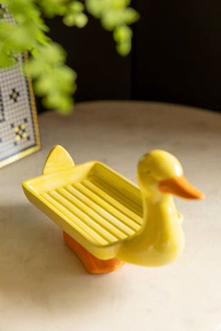 The Yellow Duck Soap Dish displayed on a marble surface.