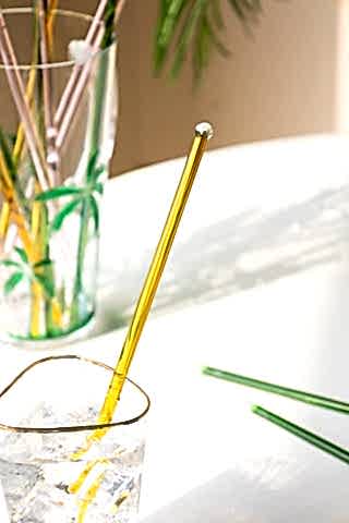 The Yellow Glass Cocktail Stirrer styled in a glass of gin on a sunny table.
