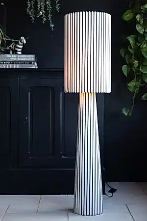 Lifestyle image of the Black & White Stripe Floor Lamp on with a black cabinet